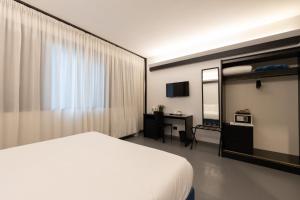 a bedroom with a white bed and a desk and a mirror at Cristal Palace Hotel in Andria