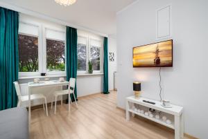 a living room with a table and chairs and windows at Apartament Stella in Częstochowa