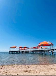 a pier with red umbrellas on the beach at Коттедж Иссык-Куль Бостери Киргизия in Bosteri