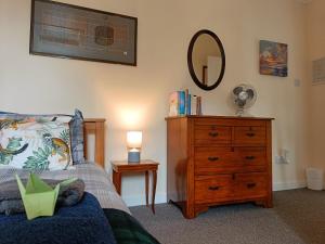 a bedroom with a bed and a dresser with a mirror at Snowberry Cottage in Borve +77 photos