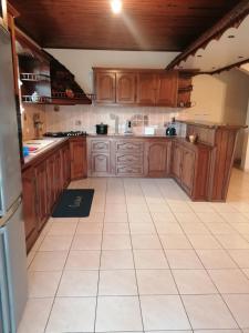 a kitchen with wooden cabinets and a white tile floor at Ti Kaz Citro'Nel in Étang-Salé
