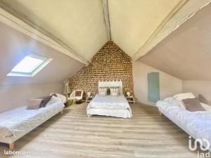 a attic bedroom with two beds and a brick wall at Cosy Campagne in Saussay-la-Campagne