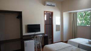 a bedroom with a tv and a bed and a chair at Pinheiros Hotel in Goiânia
