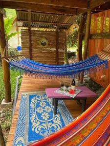 a hammock with a table on a wooden deck at A Treehouse the Green Frog Romantic setting & Pool in Puerto Viejo
