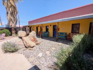 a yellow building with colorful chairs in front of it at Pelican Spa in Truth or Consequences