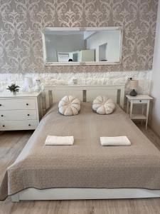 a bedroom with a bed with two pillows and a mirror at Pacsirta Apartmanház in Eger