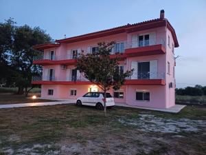 a white car parked in front of a pink building at Pefki Apartment 6 in Artemísion