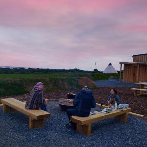 a group of people sitting on picnic tables with a dog at The Rounds in Pembrokeshire
