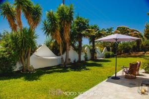 a garden with palm trees and a table and an umbrella at ViewGardenSkioni MoodSolutions Living in Mola Kalyva