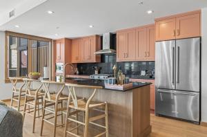a kitchen with wooden cabinets and a stainless steel refrigerator at Rundle Lux Villa at Timberstone in Canmore