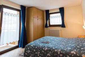 a bedroom with a bed with blue sheets and windows at Appartamento Dina in Livigno