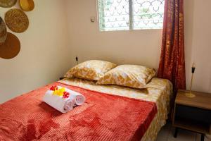 a bedroom with a bed with a red blanket and pillows at Bungalow Rubis in Le Gosier