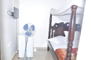 a bedroom with a wooden bed with a fan at City Side Hotels and Apartments Mukono in Mukono