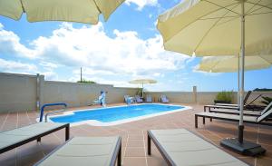 a swimming pool with two chairs and an umbrella at GALIHOST - Apartamentos Vento Mareiro in Sanxenxo