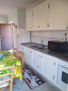 カンニジョネにあるLa casa del portoの白いキャビネットとシンクとテーブルのあるキッチン