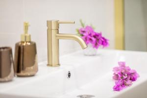 a bathroom sink with a gold faucet and purple flowers at Apartmani Doro in Vela Luka +58 photos