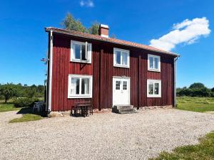a red barn with white windows on a gravel driveway at 5 star holiday home in Urshult in Urshult