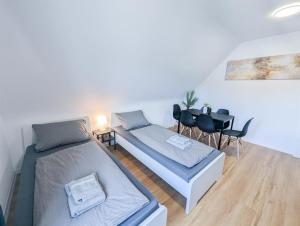 a bedroom with two beds and a table and chairs at ALFA Stuttgart 3 Zimmer 6 Betten Apartment Wasen MercedesBenz MHP Arena l Bad I Küche l WIFI & SmartTV l 3BR & 6 Beds l Bathroom l Kitchen in Stuttgart