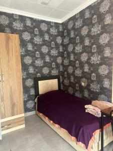 a bedroom with a purple bed with floral wallpaper at Wine Garden Apartment in Tbilisi City