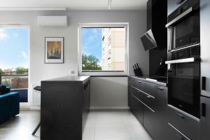 kuchnia z czarnymi szafkami i dużym oknem w obiekcie Blue Raven Downtown Apartments w Gdańsku +3 zdjęcia