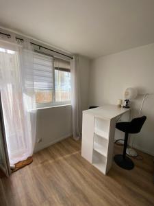 a white desk and a chair in a room with a window at Appartement proche La Villette avec 2 balcons in Pantin