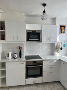 a kitchen with white cabinets and a stove top oven at Appartement proche La Villette avec 2 balcons in Pantin