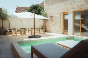 a swimming pool with a table and an umbrella at La Maison Gaïa Hôtel & Spa in Torreilles