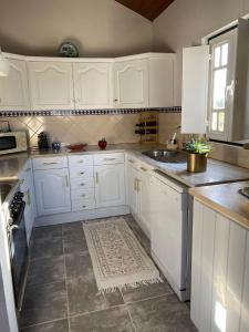 a white kitchen with white cabinets and a sink at Casa da Avó Ana - Montargil in Montargil