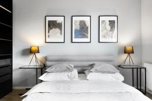 Biała sypialnia z czterema obrazami na ścianie w obiekcie Blue Raven Downtown Apartments w Gdańsku