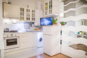 a kitchen with white cabinets and a tv on the wall at Il Gigliolo Apartment in Florence