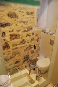 a bathroom with a toilet and a stone wall at Despina Studios in Kokkari +37 photos