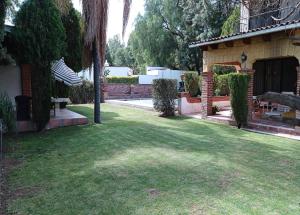 a yard with a house and a lawn with a fence at Casa Vacacional con Alberca y Asador Tequisquiapan Querétaro Club de Golf in El Sauz Tequisquiapan