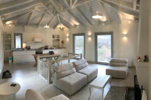 a living room with a white couch and a kitchen at Footpath House / Ολόκληρο σπίτι στο Μεγάλο Χωριό in Méga Khoríon +9 photos