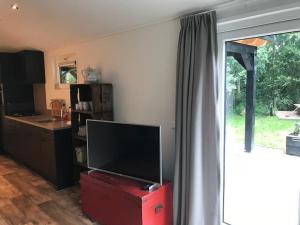 a living room with a flat screen tv on a red box at Chalet 'Het Vinkje' in Oosterwolde