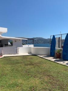 a house with a yard with blue chairs and the water at Casa Las iguanas in Acapulco