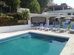 a pool with chairs and umbrellas on a patio at Casa Las iguanas in Acapulco