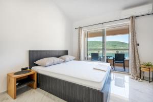 een slaapkamer met een bed en een groot raam bij Apartmani Divna in Neum