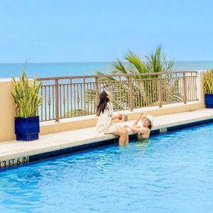 zwei Mädchen sitzen am Rand eines Schwimmbeckens in der Unterkunft Private Residences at The Atlantic Resort & Spa in Fort Lauderdale + 26 Fotos