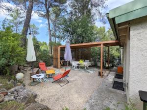 eine Terrasse mit Tisch und Stühlen und einem Sonnenschirm in der Unterkunft Charmante Maison en pleine nature avec piscine in Assas