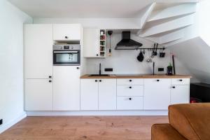 a kitchen with white cabinets and a staircase at vakantie-hengelhoef in Houthalen-Helchteren