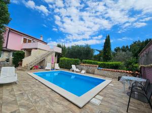 a swimming pool in a yard with a house at Villa Kate, with a private swimming pool and garden in Malinska