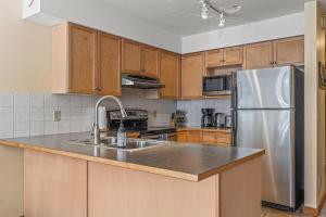 a kitchen with a stainless steel refrigerator and wooden cabinets at C303 Hidden Gem with MTN andCreek View, Quiet and Private in Canmore