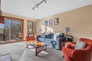 a living room with a blue couch and two chairs at C303 Hidden Gem with MTN andCreek View, Quiet and Private in Canmore