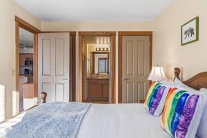 a bedroom with a white bed with colorful pillows at C303 Hidden Gem with MTN andCreek View, Quiet and Private in Canmore