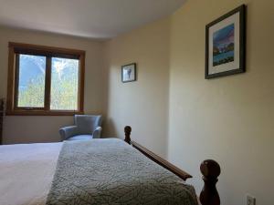a bedroom with a bed and a chair and a window at C303 Hidden Gem with MTN andCreek View, Quiet and Private in Canmore
