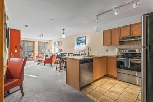 a kitchen with a stove top oven next to a living room at C303 Hidden Gem with MTN andCreek View, Quiet and Private in Canmore