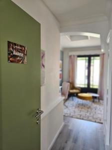 a hallway with a green door and a living room at Lazy Olives in Tongeren