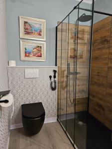 a bathroom with a shower and a black toilet at Lazy Olives in Tongeren
