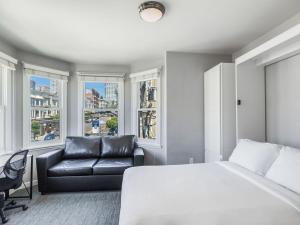 a bedroom with a bed and a couch and windows at The Dorel SF in San Francisco
