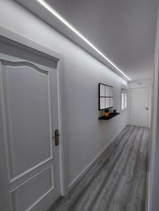 Habitación blanca con puerta y pasillo en El nido de la gaviota, en Moaña